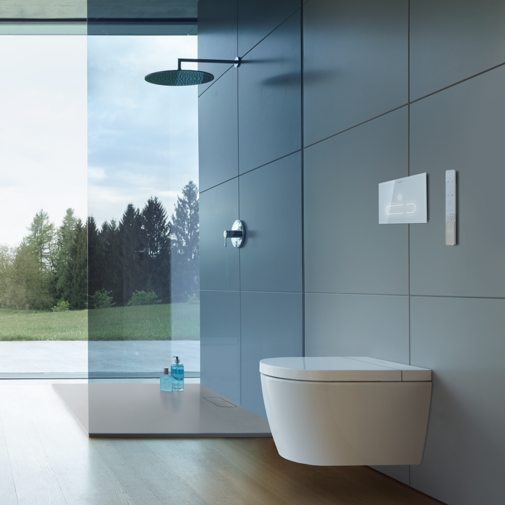 Starck f Lite SensoWash vägghängd toalett på en kaklad vägg i ett badrum med en dusch i bakgrunden.