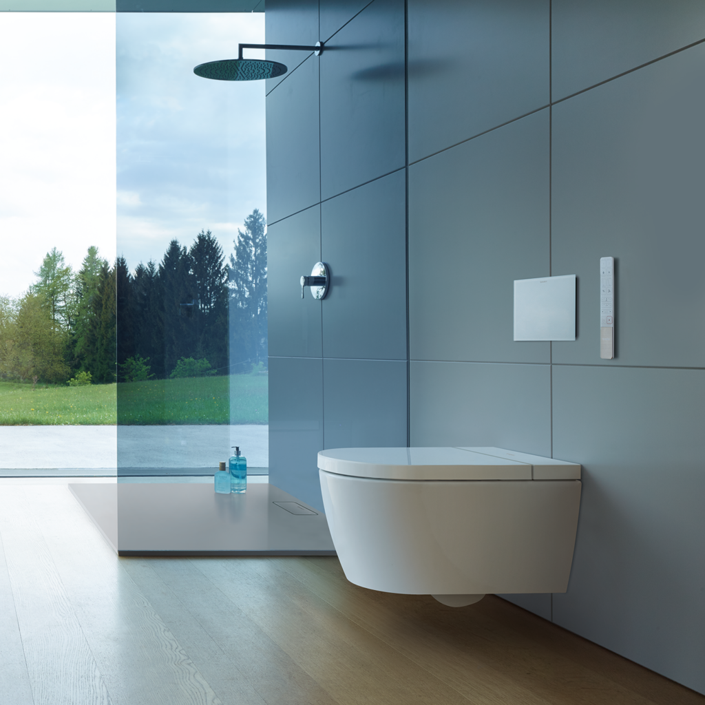 Starck f Lite SensoWash vägghängd toalett på en kaklad vägg i ett badrum med en dusch i bakgrunden.