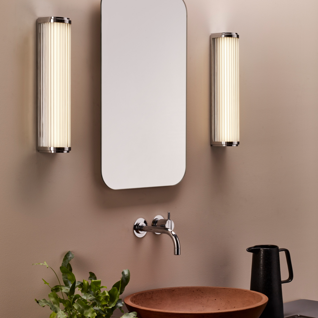 Versailles 370 LED sitter på en badrumsvägg på vardera sida om en spegel och över ett tvättställ.