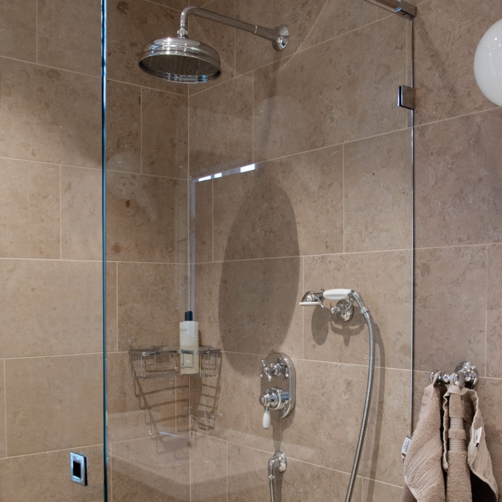 Roma inbyggnadsdusch i en klassisk lantlig stil. Sittandes på en kaklad vägg med en genomskinlig duschvägg.