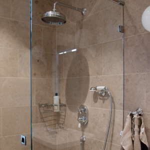 Roma inbyggnadsdusch i en klassisk lantlig stil. Sittandes på en kaklad vägg med en genomskinlig duschvägg.