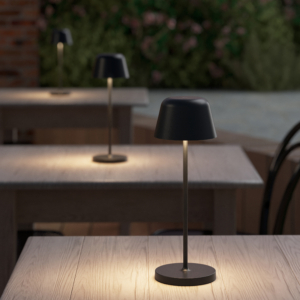 Nomad bordslampa på ett cafebord i en trädgård.